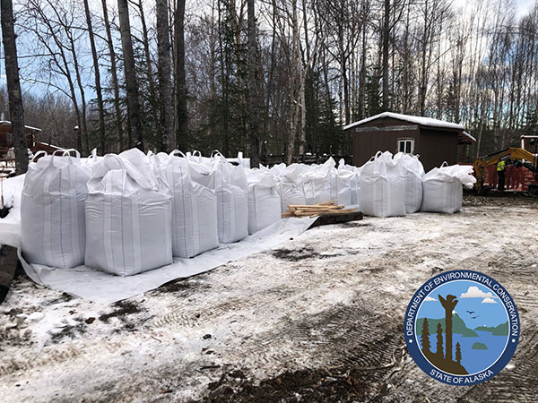 Image shows many bags of contaminated soil next to a home, ready for disposal